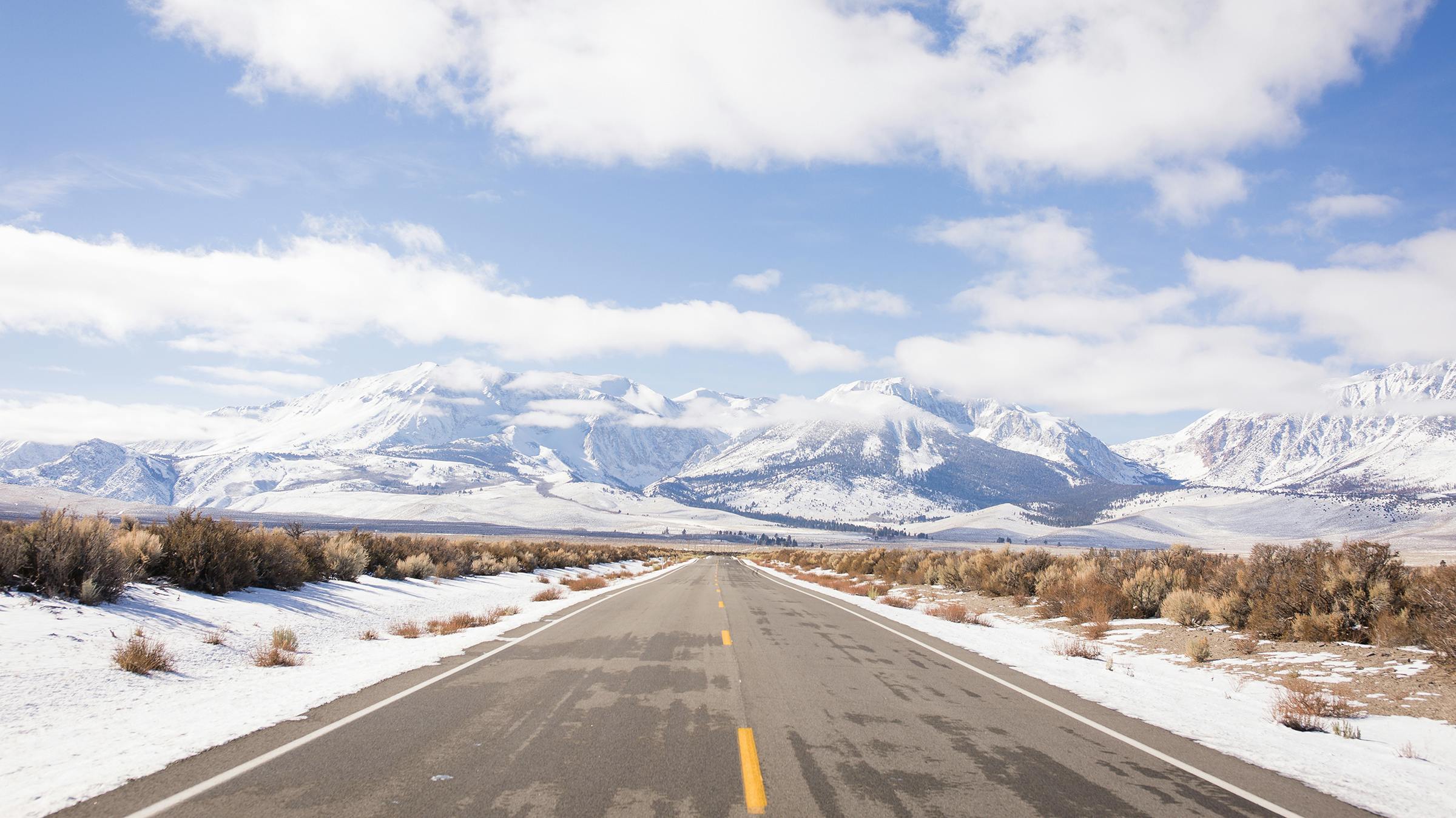 Scenic photo of road with new snow on mountains