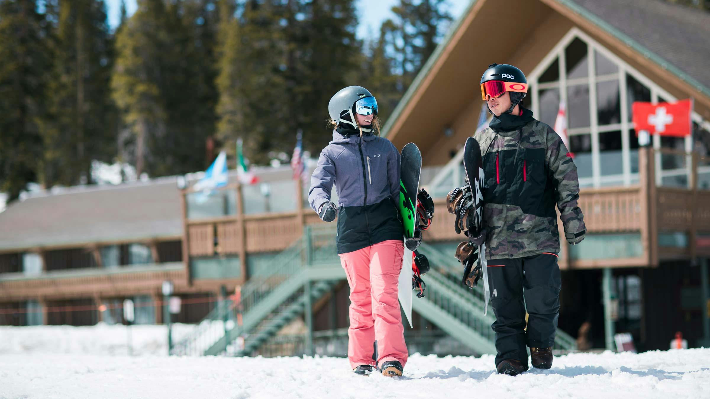 Snowboarders walking in front of Mammoth Mountain Inn