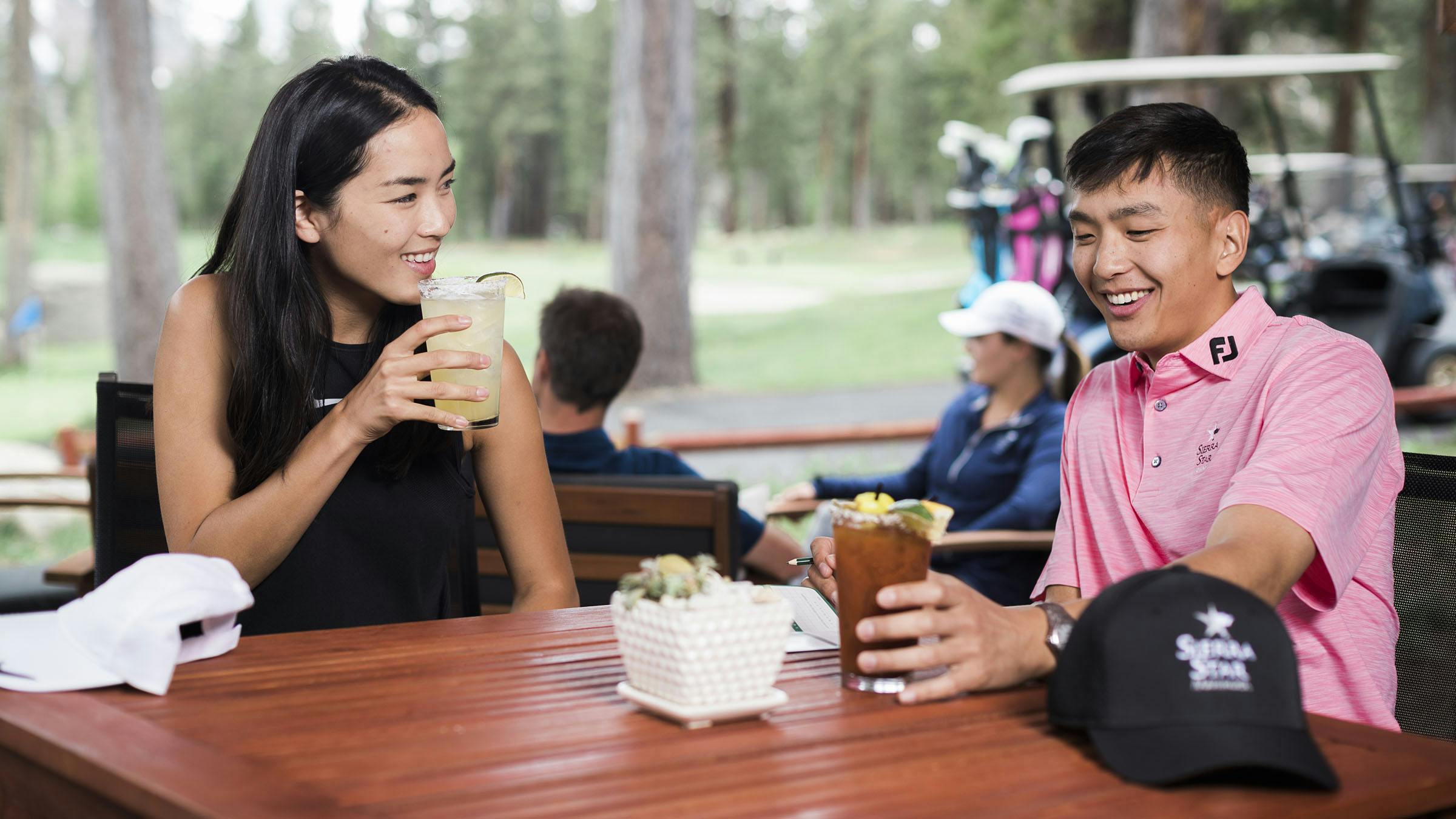 Woman and man drinking cold beverages at Chip Shot Cafe with golf cart in the background