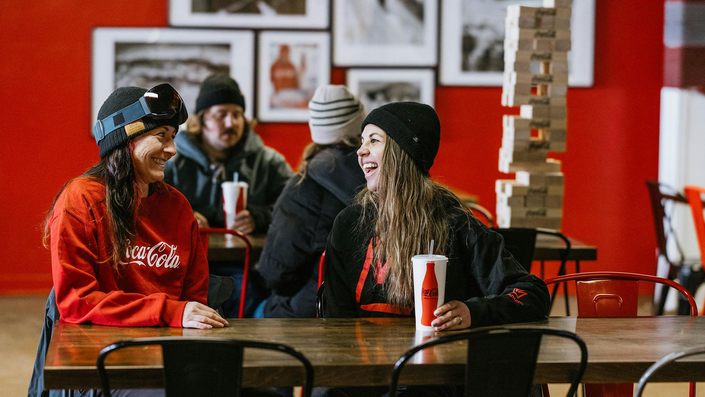 Two friends seated at table drinking Coca-Cola 