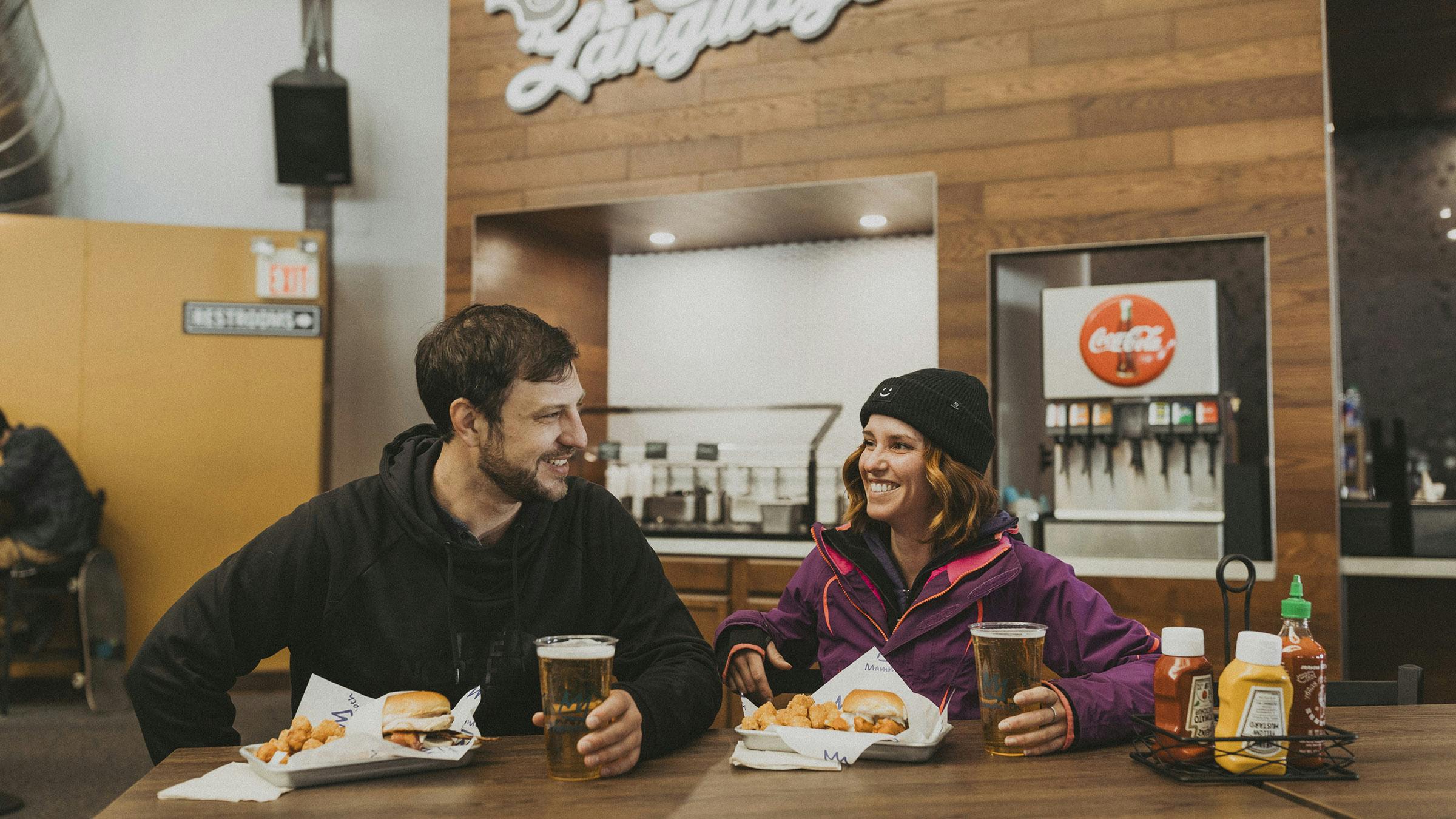 Smiling man and woman enjoying draft beers and chicken sandwiches
