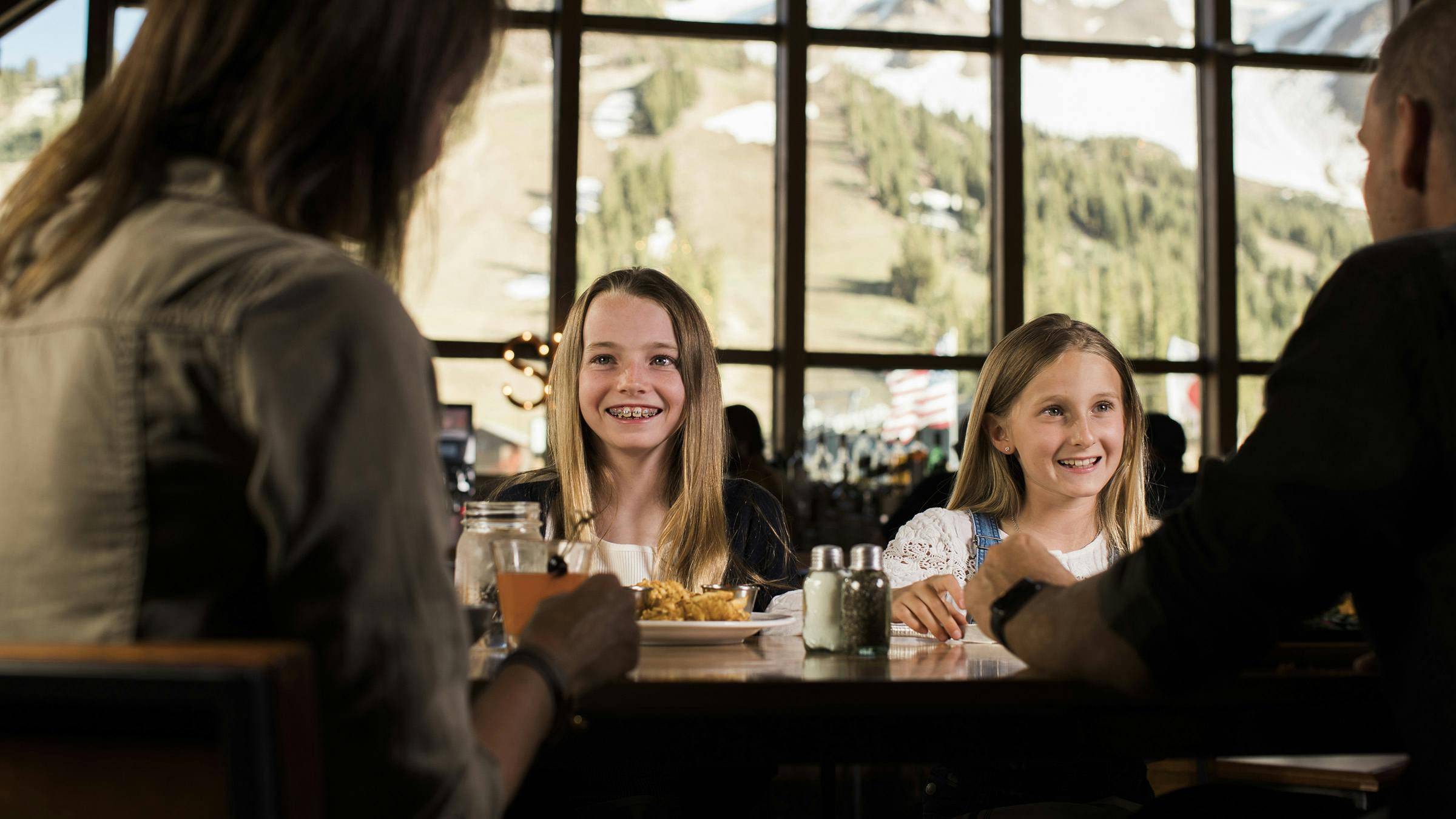 Family dining at Mountainside Bar and Grill with view of Mammoth Mountain outside of the window