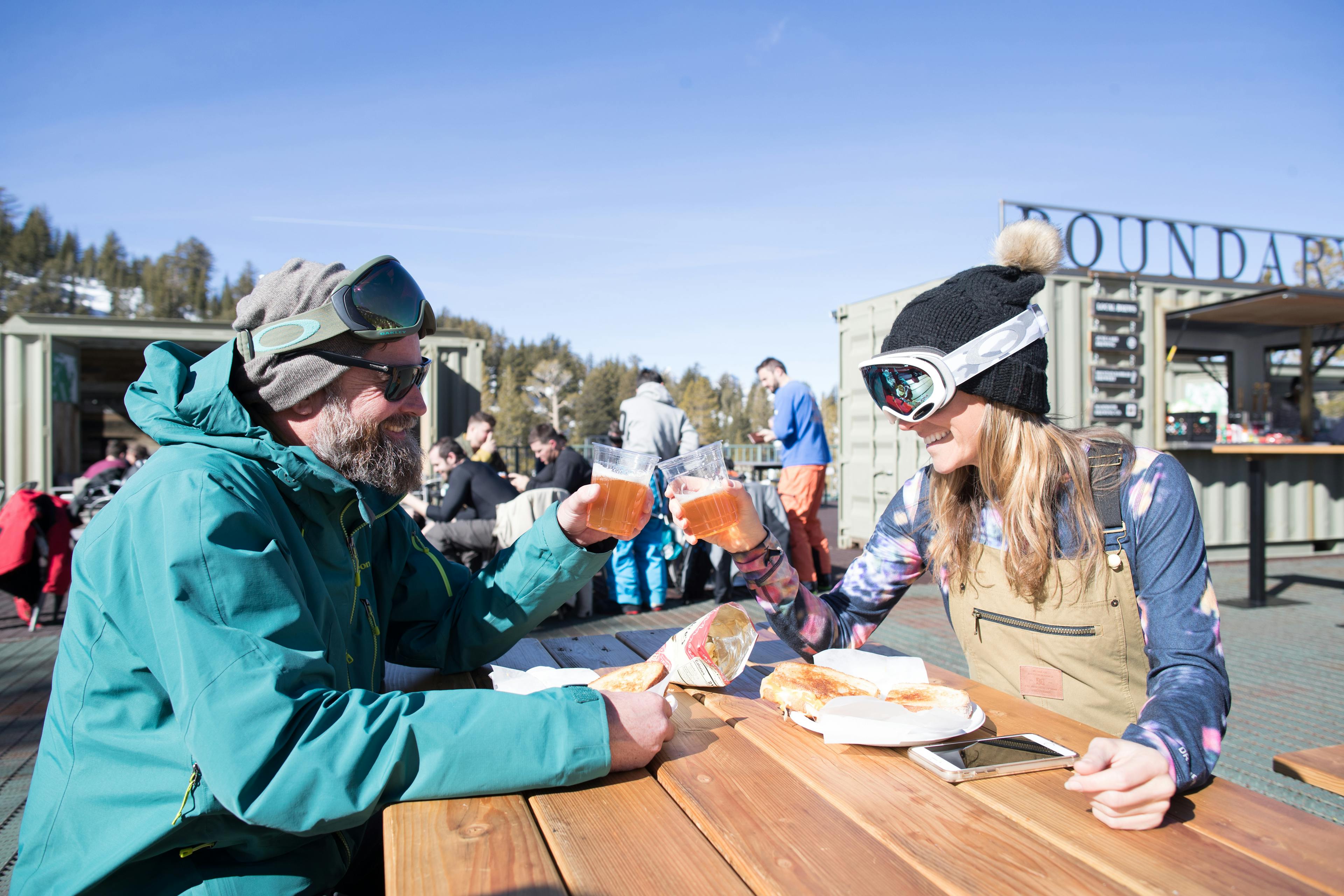 Man and woman in ski gear enjoying grilled cheese sandwiches at the Outpost
