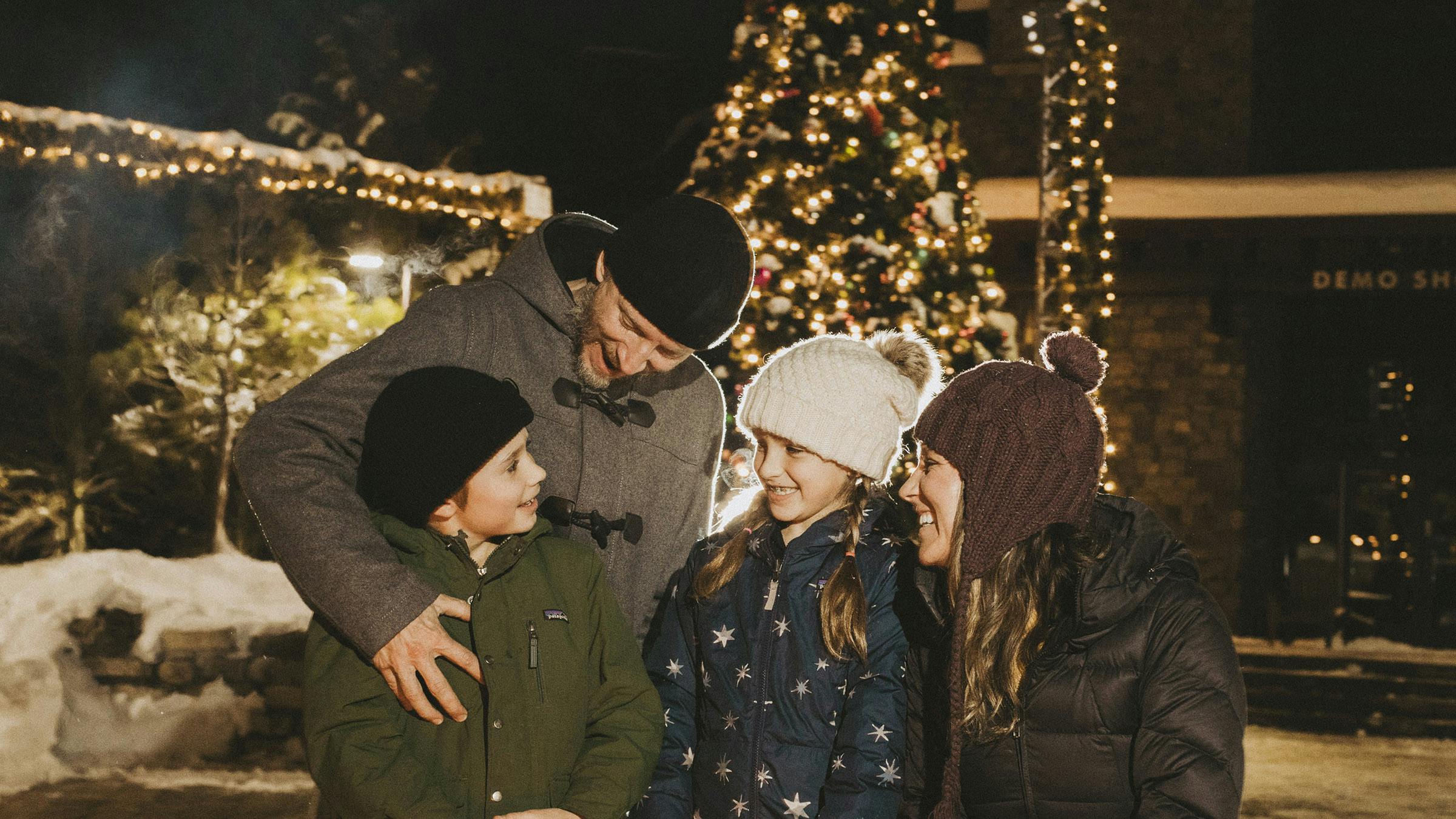 Smiling family in front of holiday tree lights