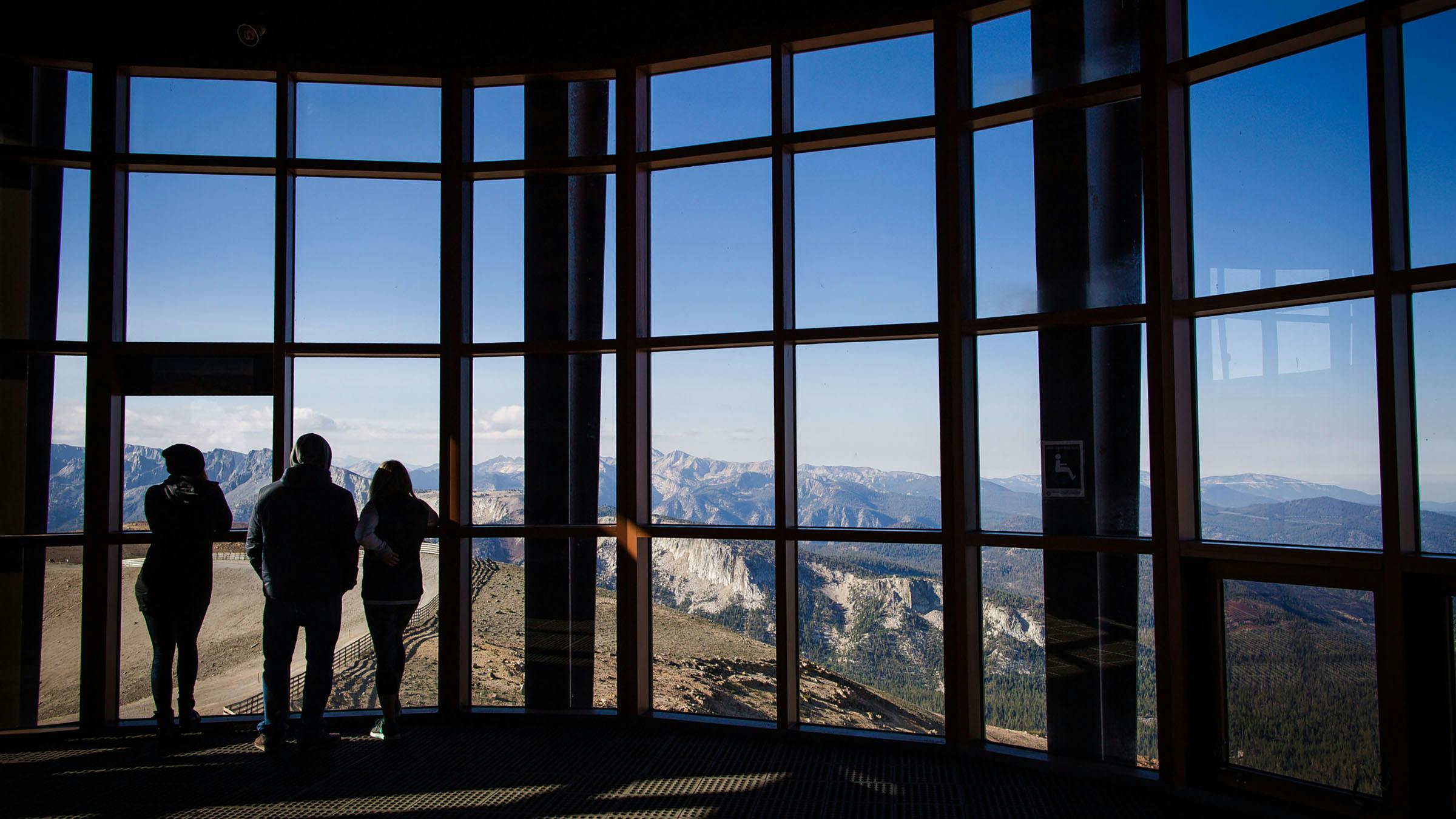 Silhouette of guests looking out the windows at the Eleven53 Interpretive Center on the summit of Mammoth Mountain
