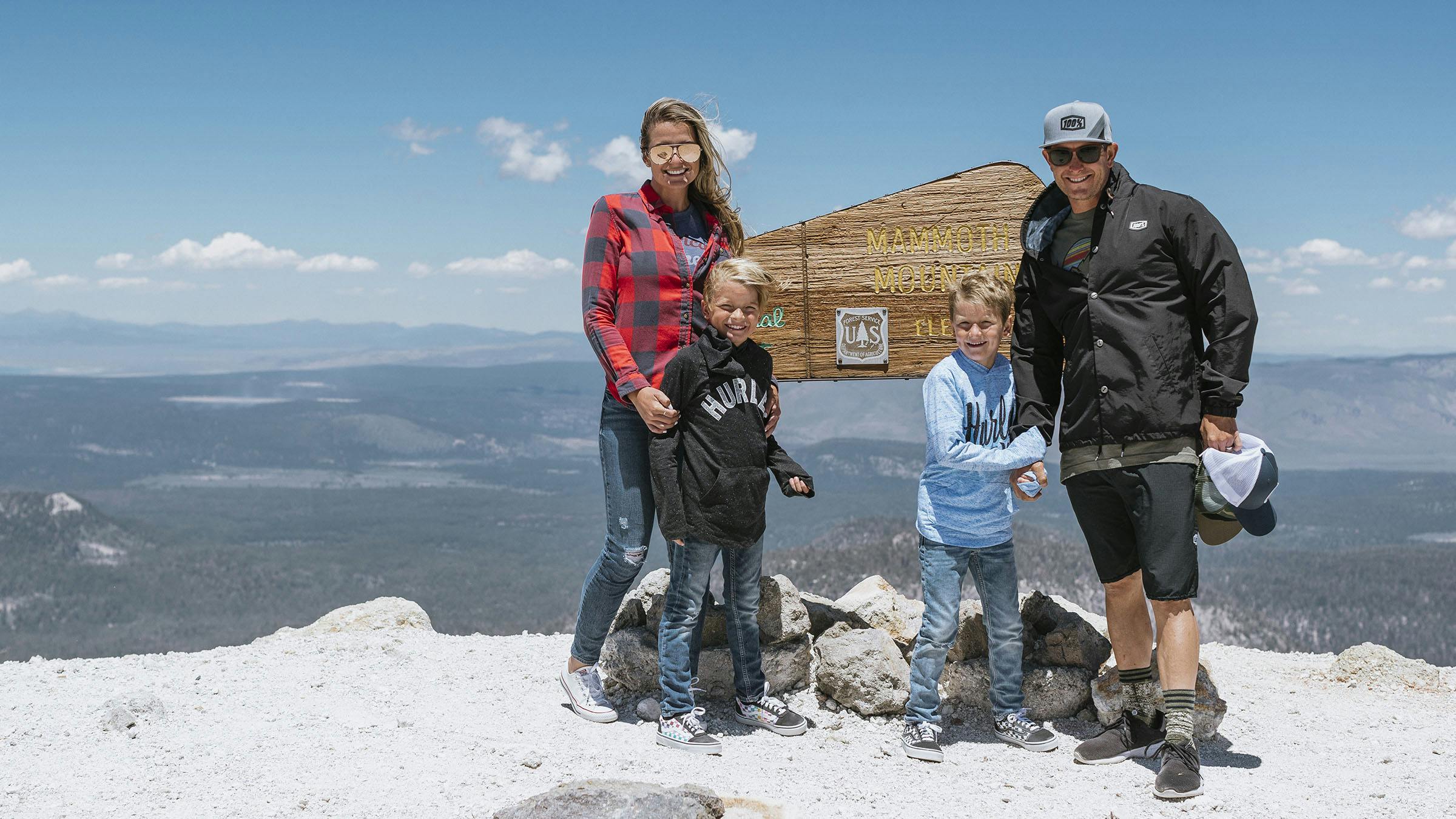 Family standing next to Mammoth Mountain sign