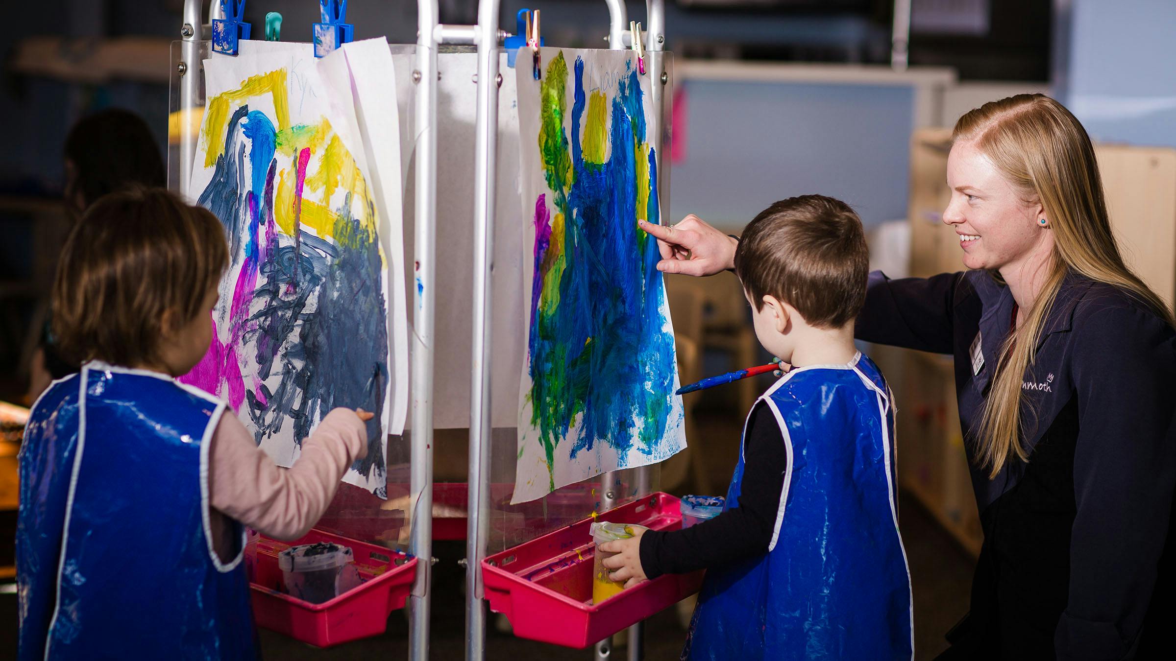 Two children painting with child care instructor