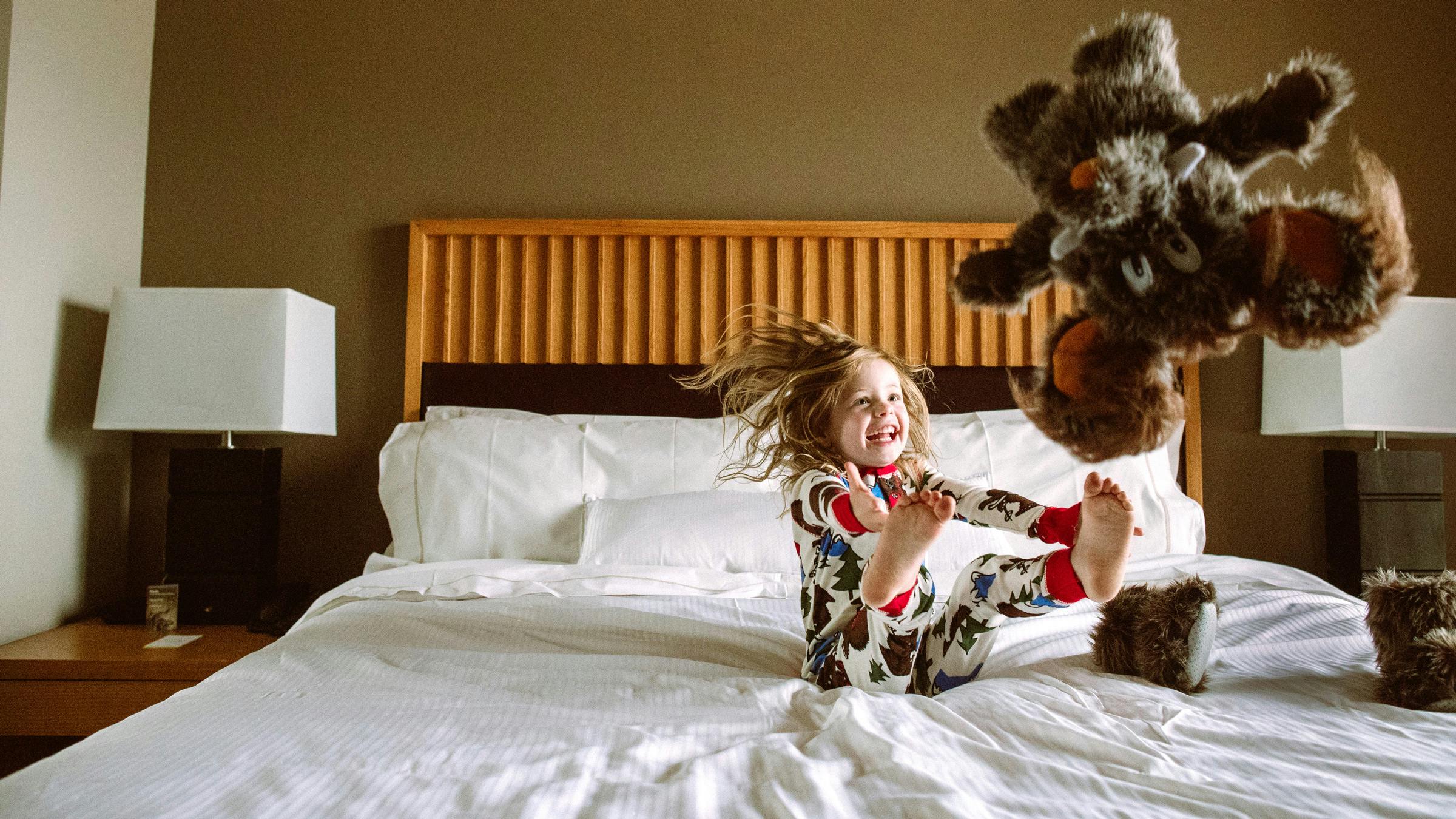 Kid in Mammoth pajamas jumping on bed
