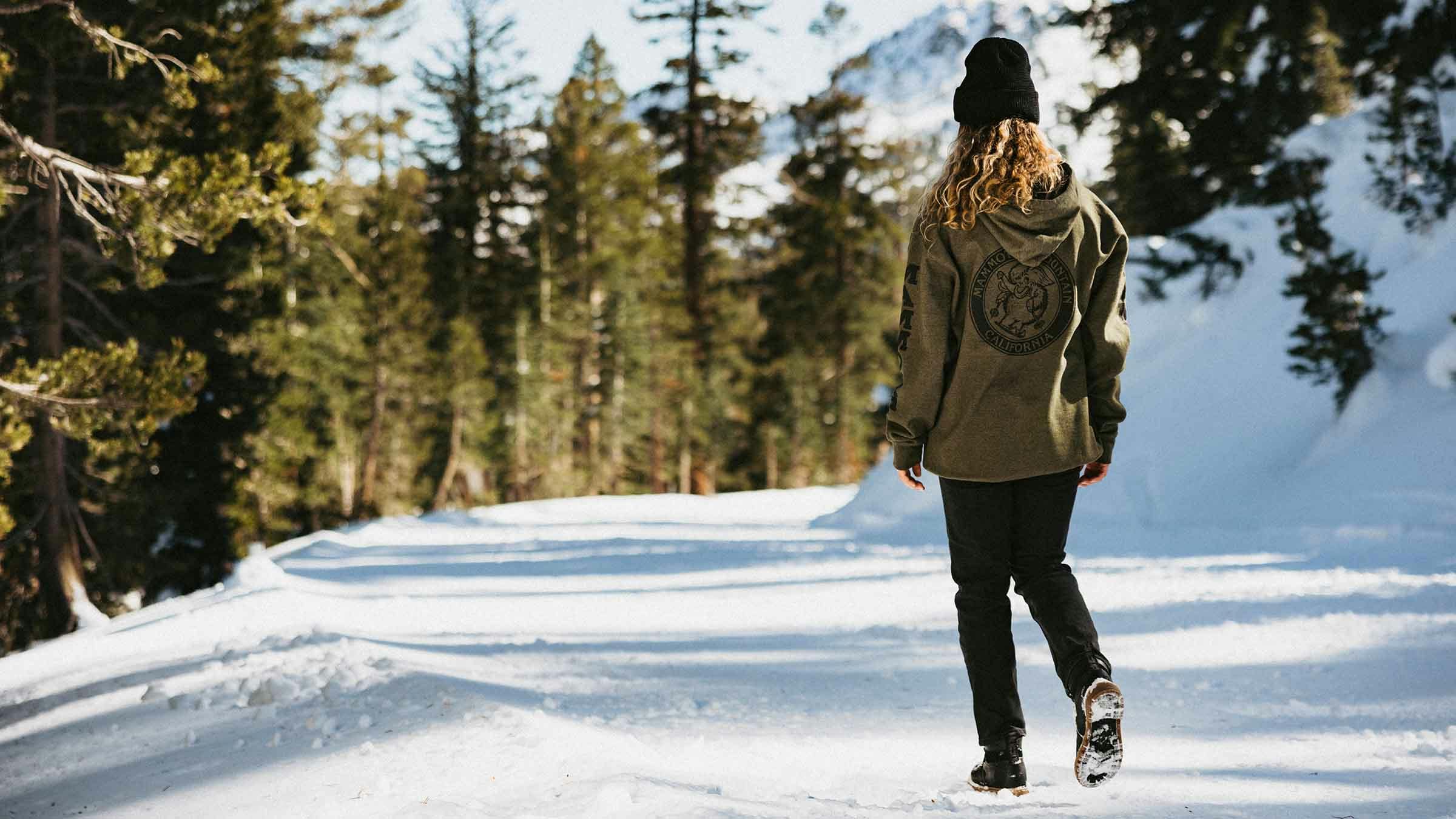 Girl walking through the snow with a Mammoth hoodie