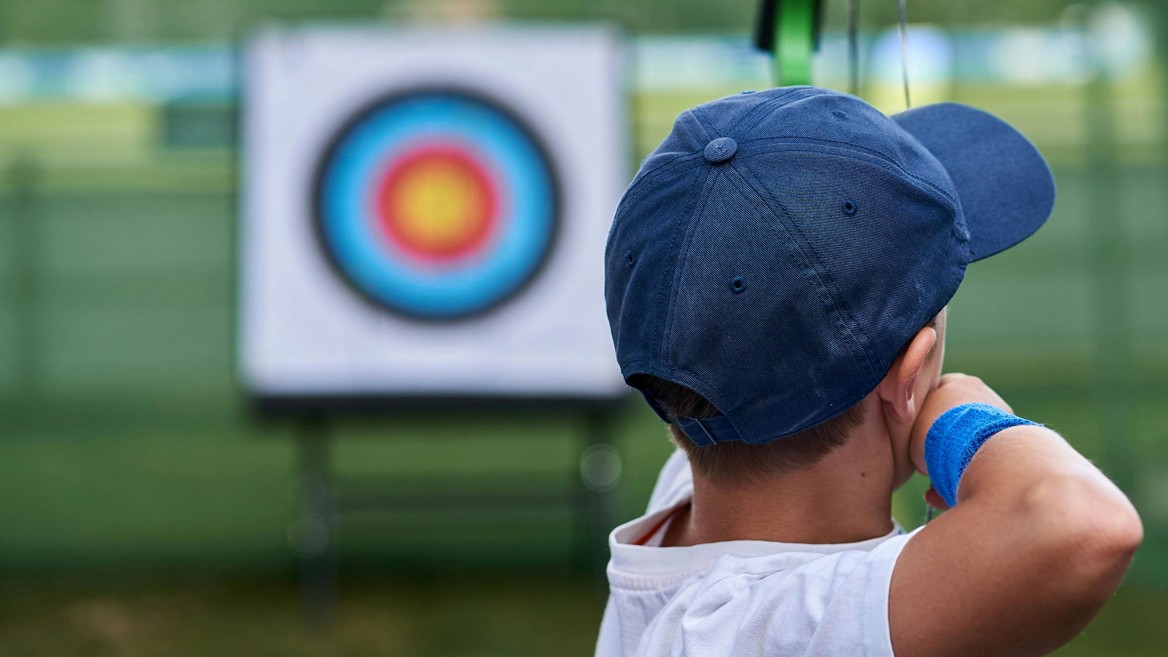 Stock photo of young boy aiming at a target with his bow and arrows