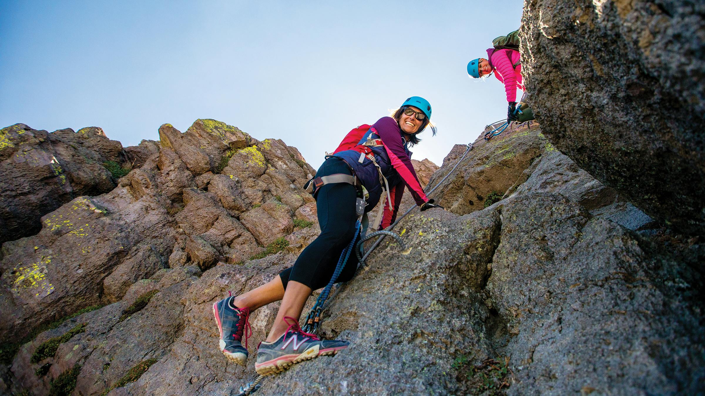 Two women climbing the Via Ferrata on the cliffs off Mammoth Mountain