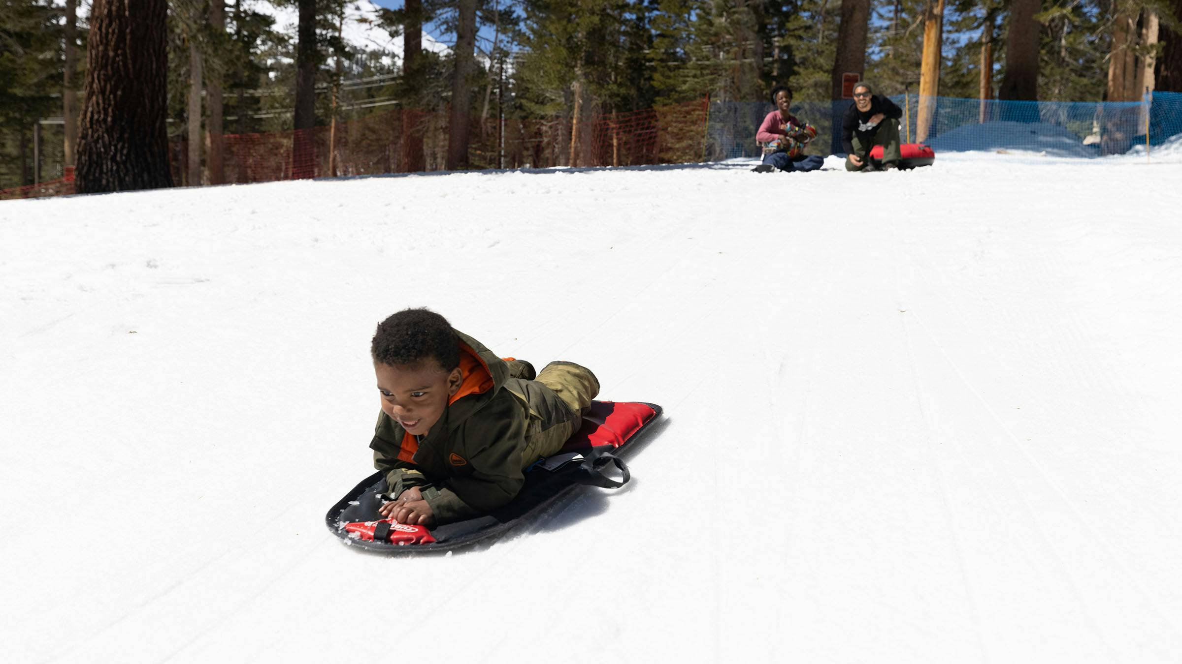 Child sliding on sled in snow play area