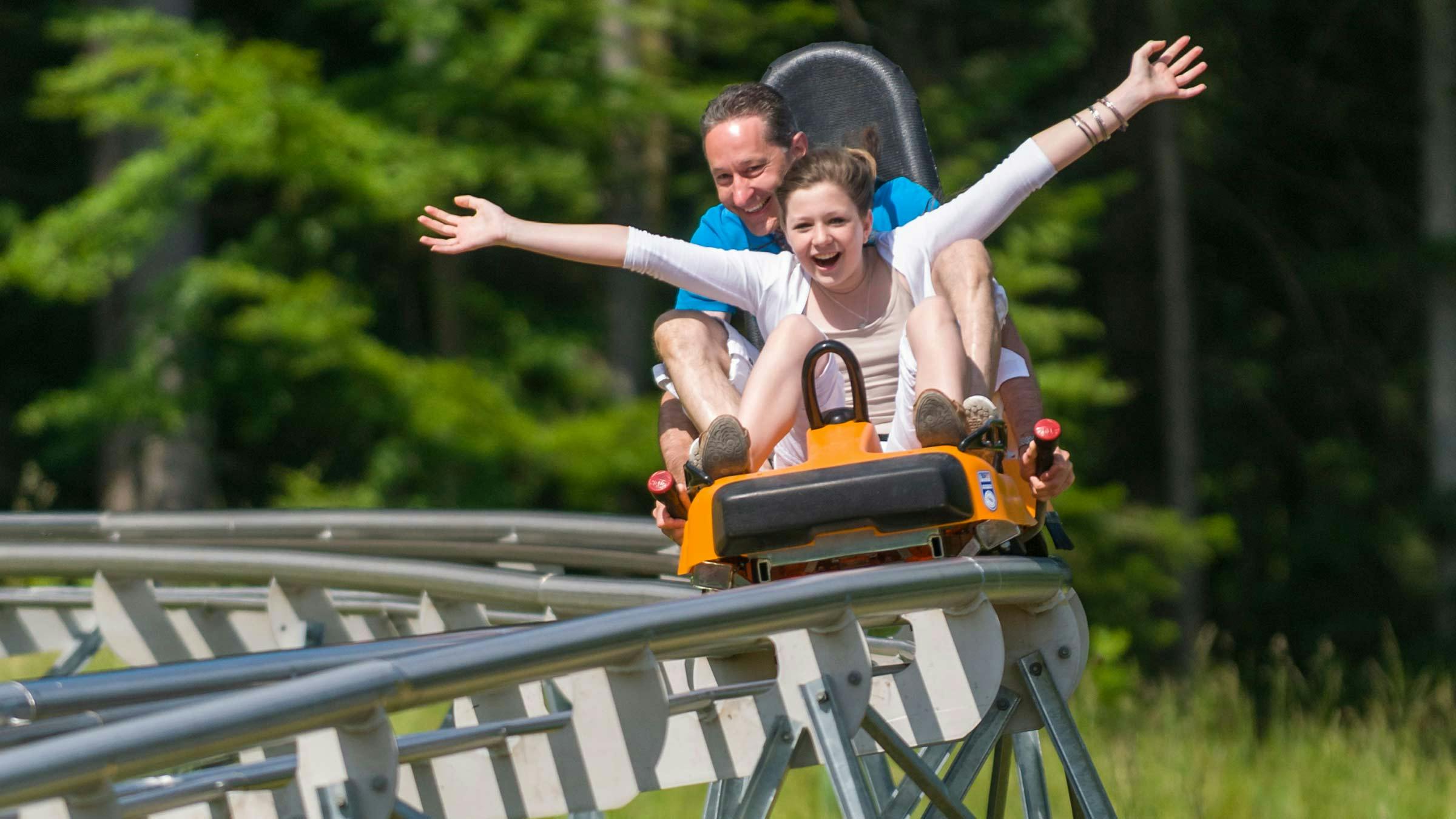 Father and daughter riding the mountain coaster